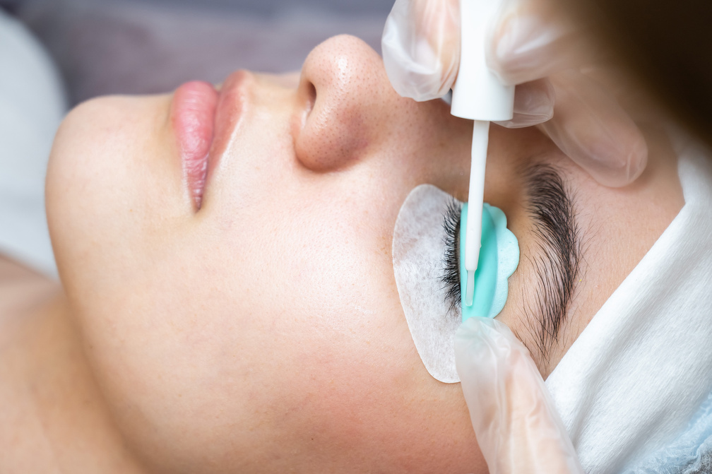 Young woman undergoing eyelash tinting and lamination procedure.